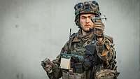 Ein Soldat hält eine kleine Drohne in der Hand.