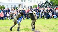 Zwei Soldaten führen eine Nahkampfvorführung vor einigen Besuchern vor.
