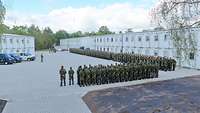 Mehr als 200 Soldatinnen und Soldaten stehen in Formation, im Hintergrund Unterkunftsgebäude