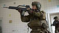 Ein Soldat, mit einem Gewehr G36 im Anschlag stürmt in einen weiß gekachelten Raum.
