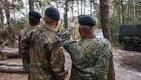 Soldaten stehen in einem Waldstück mit einem Bohrgerät.
