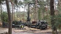 Ein Bohrgerät steht in einem Waldstück.