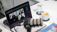 Ein Soldat sitzt mit Kopfhörern vor einem Laptop und spricht in einer Konferenz mit weiten Personen