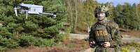Ein Soldat kniet im Gelände und steuert eine Drohne vom Typ Autel.
