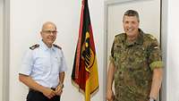 Zwei Soldaten stehen in einem Büro vor einer Bundesdienstflagge