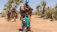 Zwei malische Kinder laufen neben deutschen Soldaten