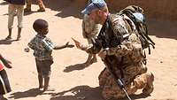 Deutscher Soldat und ein malisches Kind begrüßen sich mit Handschlag