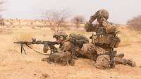 Zwei Soldaten der Bundeswehr im Gelände, einer mit Maschinengewehr im Anschlag und einer beobachtet mit einem Doppelfernrohr