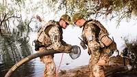 Zwei Soldaten mit einem bereiten den Schlauch vor