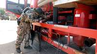 Eine Soldatin untersucht ein Tankfahrzeug mit Taschenlampe