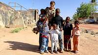 Eine Soldatin steht mit mehreren malischen Kindern zusammen