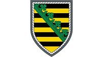 Neunfach schwarz und gold geteilt, belegt mit einem diagonalen grünen Rautenkranz, silbern umrandet.