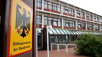 Das Bildungszentrum der Bundeswehr Ein Gebäude mit vielen Fenstern von außen. Links im Bild ist ein Wappen mit dem Bundesadler.