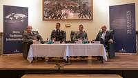 Vier Soldaten sitzen auf einer Bühne