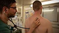 Ein Arzt hört mit einem Stetoskop die Atmung eines Patienten ab