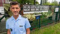 Hauptmann Dohmen aus dem Karrierecenter Düsseldorf steht in Uniform vor einem Werbebanner der Stretkräfte.