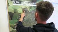Bewerber fährt mit dem Finger über eine Landkarte von Deutschland