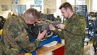 Zwei Soldaten schrauben an einem Triebwerk in einem Unterrichtsraum.