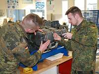 ZAW Ausbildung Luftfahrzeugtechniker in Kassel Zwei Soldaten schrauben an einem Triebwerk in einem Unterrichtsraum.