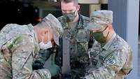 Ein Soldat steht mit zwei georgischen Soldaten an einem Tisch, darauf eine Granatmaschinenwaffe.