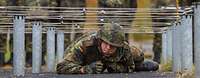 Soldat kriecht unter einem Hindernis durch