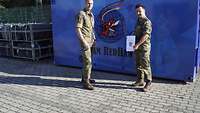 Oberleutnant Fabian Fritzsche steht mit seinem Kommandeur, Oberstleutnant Kai Mirow, vor einem blauen Container.