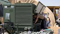 Über eine Klappe überprüft ein Soldat den Innenraum eines Generators