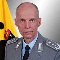 Porträt von Oberst Thomas Nikolai mit Nationalflagge im Hintergrund