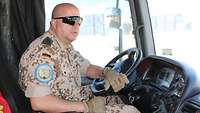 Ein Soldat sitzt auf dem Fahrersitz eines Sattelschleppers und blickt durch die Frontscheibe