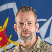 Ein dänischer Soldat mit Bart schaut freundlich in die Kamera.