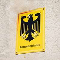 Bundesadler auf Blechschild an einem Gebäude.