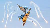 Zwei Eurofighter in der Luft. Um sie herum leuchten Hitzetäuschkörper, sogenannte Flares, die sie abgeschossen haben.