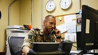 Ein Soldat sitzt am Schreibtisch und telefoniert