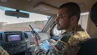 Ein deutscher Soldat sitzt im Auto und hält ein Funkgerät in der Hand 