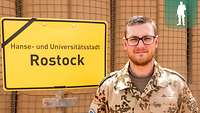 Ein deutscher Soldat steht vor dem Ortsschild Rostock im Camp Castor