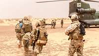 Die Soldaten gehen mit den Verwundeten auf den gelandeten Hubschrauber zu