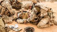 Soldaten tasten einen verletzten Soldaten nach Verletzungen ab.