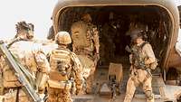 Ein verwundeter Soldat wird von Soldaten in einen Hubschrauber getragen. 