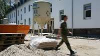 Ein Soldat in Uniform geht über eine Baustelle.