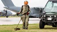 Ein Mitarbieter der Geländebetreuung bei Mäharbeiten auf einem Flugplatz, im Hintergrund der Airbus A400M.