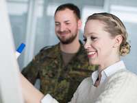 Zivile Laufbahnen bei der Bundeswehr: Soldaten und zivile Mitarbeiter arbeiten Hand in Hand Frau und Soldat stehen vor Flipchart