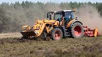 Ein Traktor der Geländebetreuung fährt mit einem Mulcher über eine Grünfläche auf einem Truppenübungsplatz.