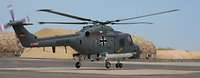 Hubschrauber vom Typ Sea Lynx Ein Hubschrauber startet von einem Flugplatz, im Hintergrund steht ein großes getarntes Zelt.