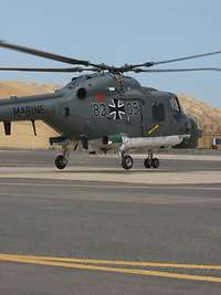 Hubschrauber vom Typ Sea Lynx Ein Hubschrauber startet von einem Flugplatz, im Hintergrund steht ein großes getarntes Zelt.