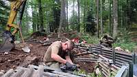 Mehrere Soldaten arbeiten mit Trennschleifern. Ein Minibagger steht für Aushubarbeiten bereit. 