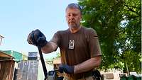 Ein Soldat zieht mit einer mechanischen Maschine die Stahlbänder um einen Kunststoffbehälter fest