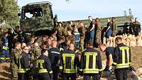 Soldaten der Bundeswehr und der polnischen Armee sowie Angehörige des Technischen Hilfswerkes beim Verladen von Sandsäcken.