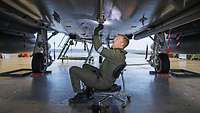 Ein Fluggerätemechaniker unter einem Eurofighter am arbeiten