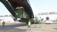 Ein grüner Containertank wird in den Laderaum eines Transportflugzeugs gehoben.