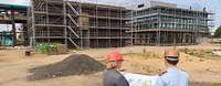 Kontrolle des Baufortschrittes auf der Baustelle in Euskirchen Eine Frau und ein Mann in Uniform schauen gemeinsam auf eine große Karte, im Hintergrund eine Baustelle.